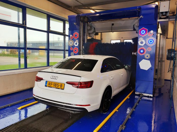 Een witte auto in onze wasstraat tussen de blauwe borstels